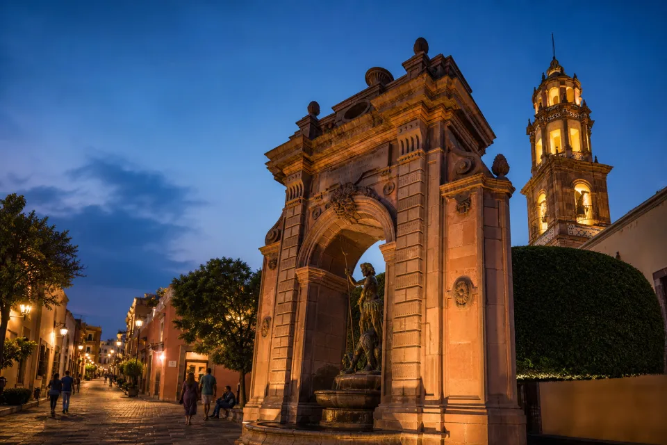 Arco de cantera y torre colonial iluminados en el Centro Histórico de Querétaro